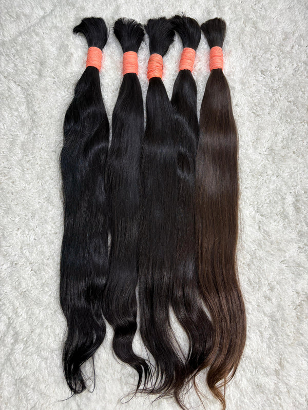 Multiple packs of raw Indian straight bulk hair extensions laid out on a surface.