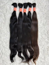 Multiple packs of raw Indian straight bulk hair extensions laid out on a surface.